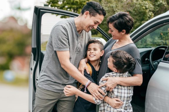 Family hugging by vehicle
